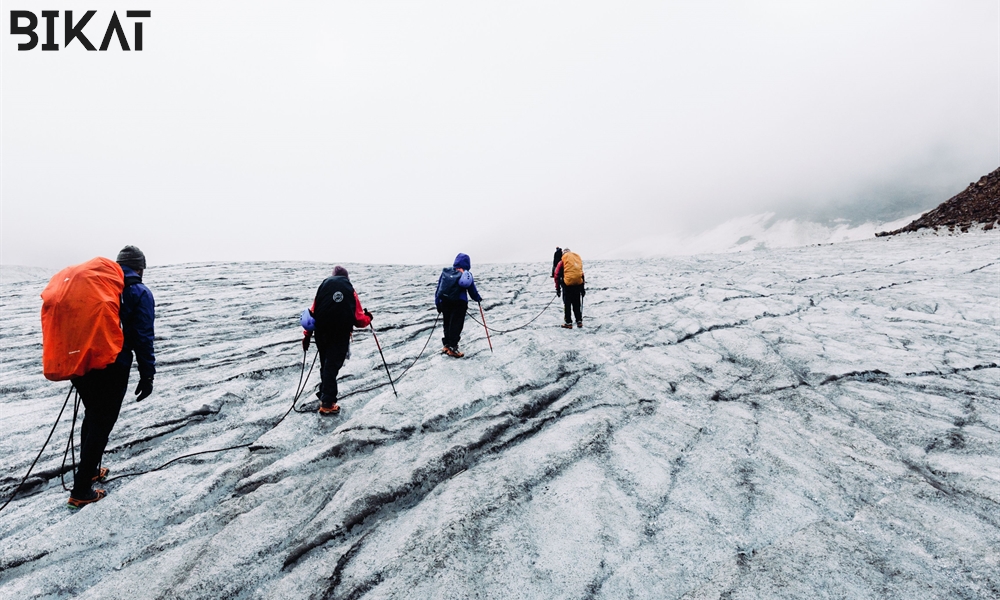 4- trekkers connected with ropes moving towards summit through the white mountains 